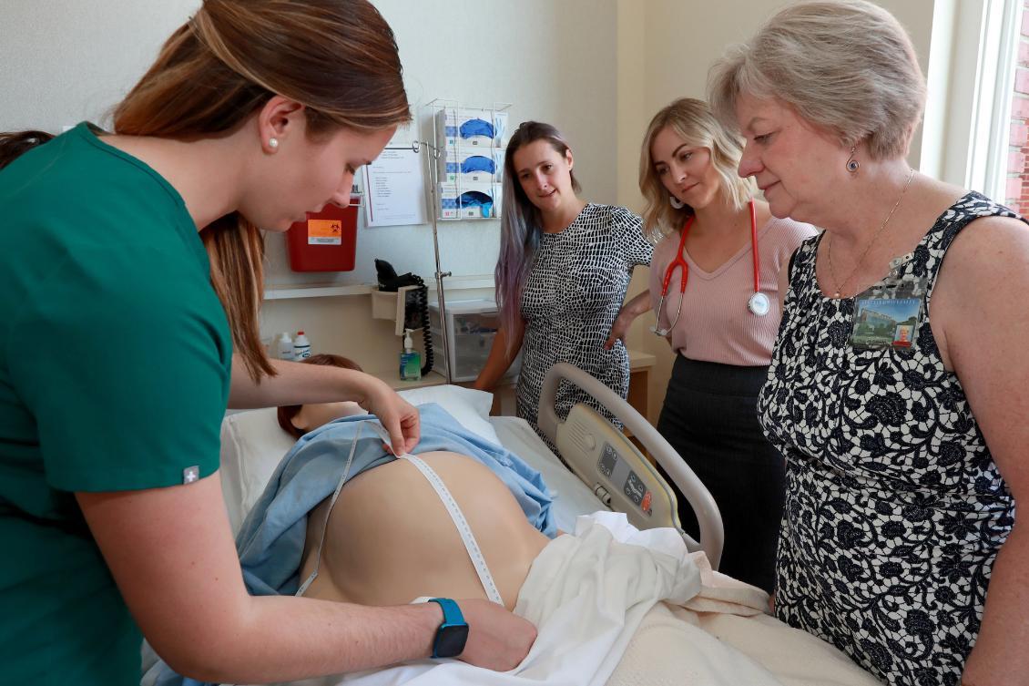 A class of Doctor of Nuring Practice students in the Nurse Midwifery progam working with a faculty member on a simulation