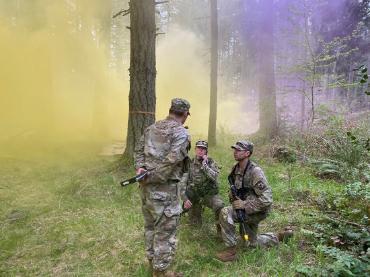 cadets in the green in the field with smoke