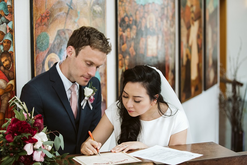 a newlywed couple signs their marriage license in front of the Chapel icons of St. Ignatius