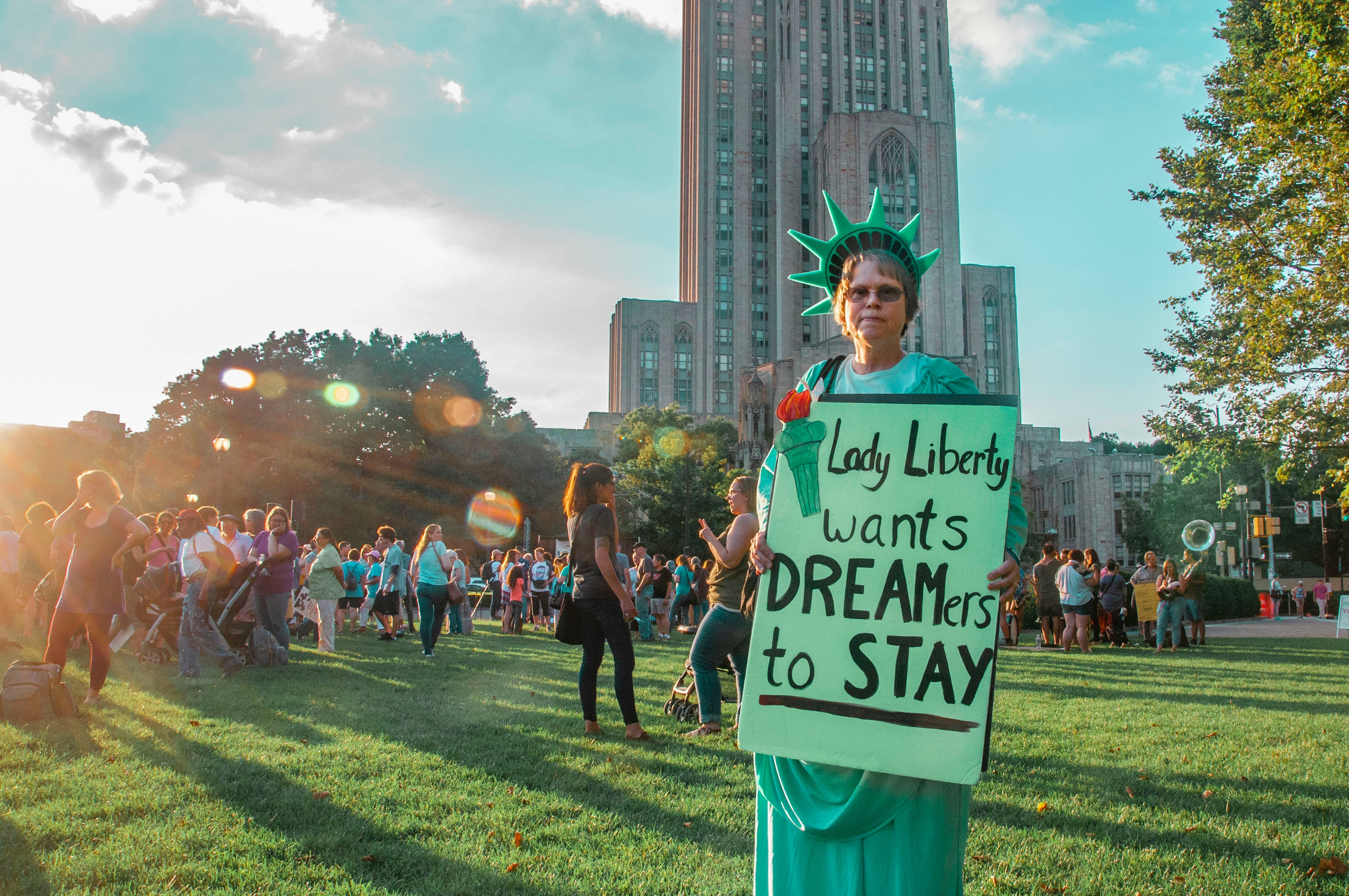 Person dressed as the Liberty Statue holding a big pamphlet that reads: Lady Liberty wants dreamers to stay