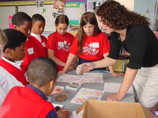 A teacher showing different kinds of rocks to students
