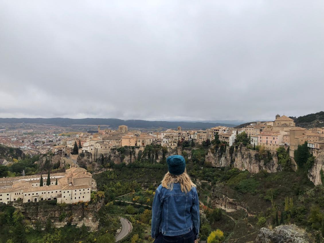 Back of a woman looking out from a mountain top to a sprawling European town below