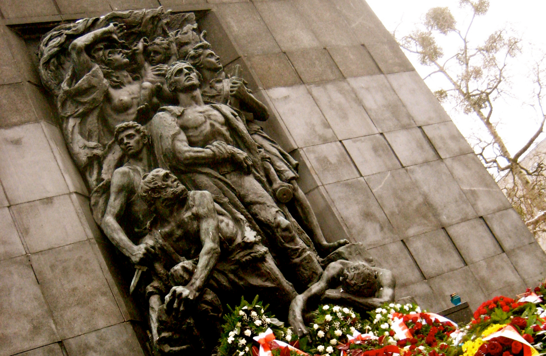 Diagonal view of a sculptured memorial of men and wreaths at the foot of the monument