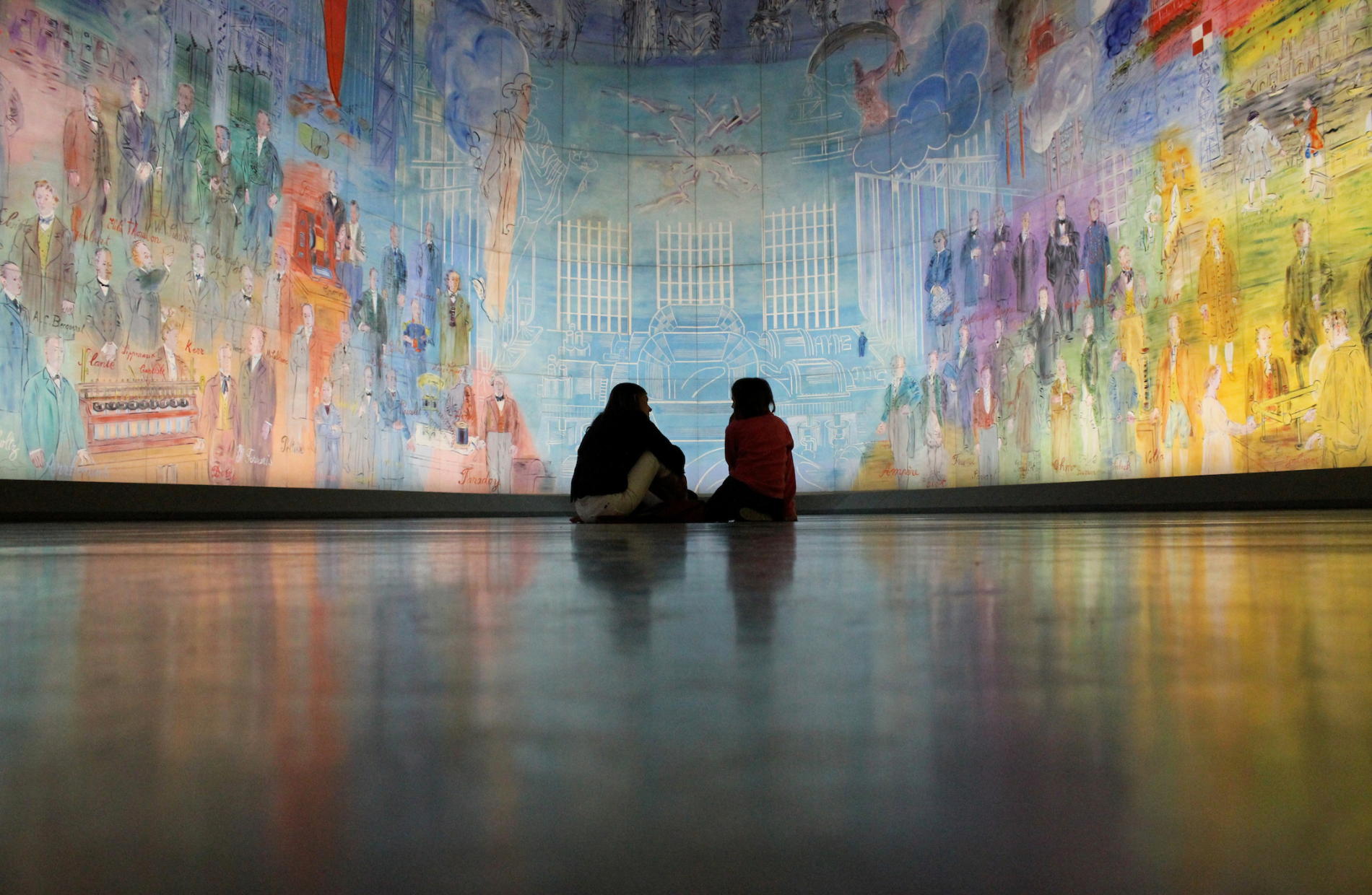 the backs of two people looking towards a colorful art mural