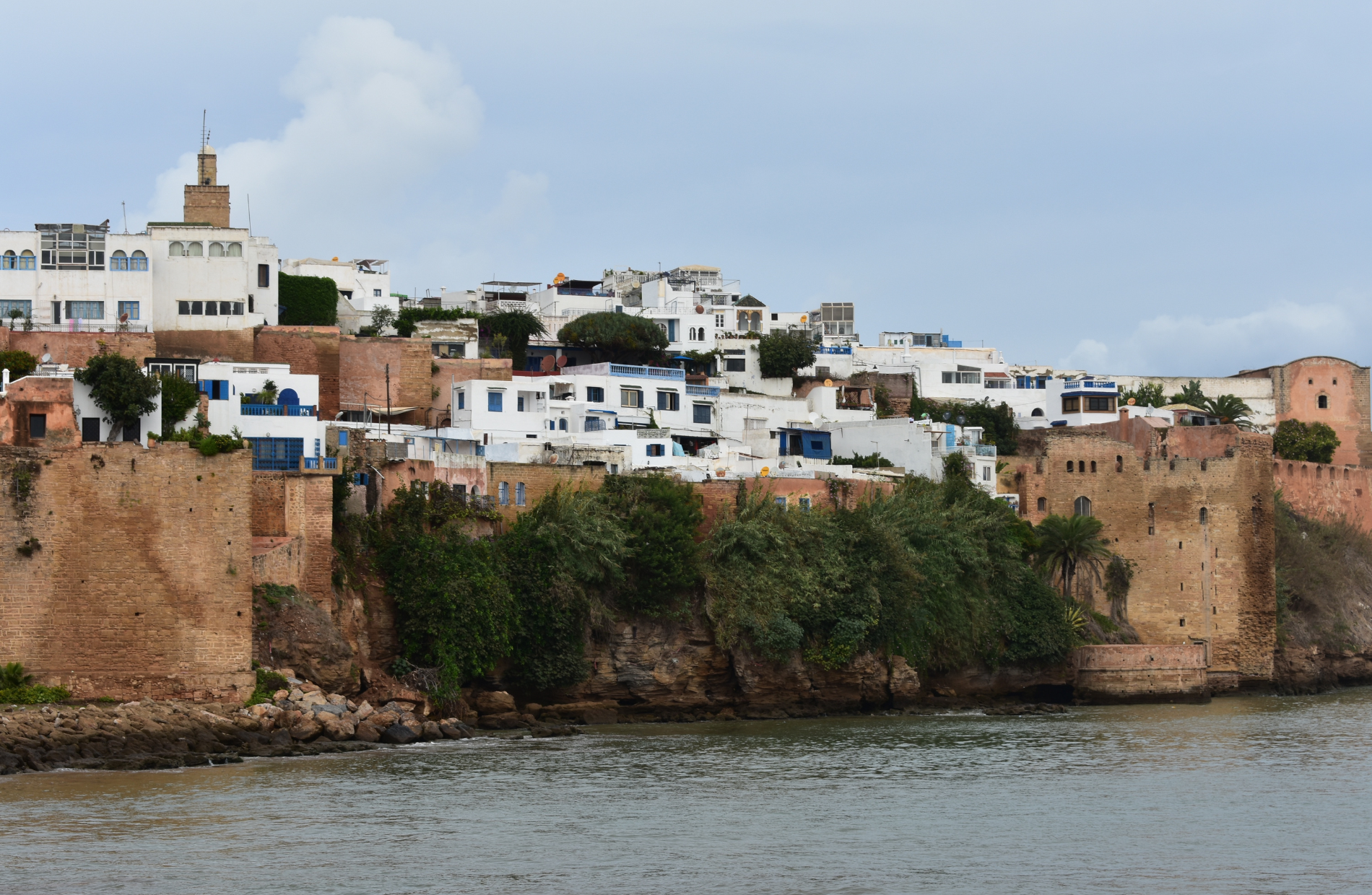 view from the water towards a cliffside lined with white houses