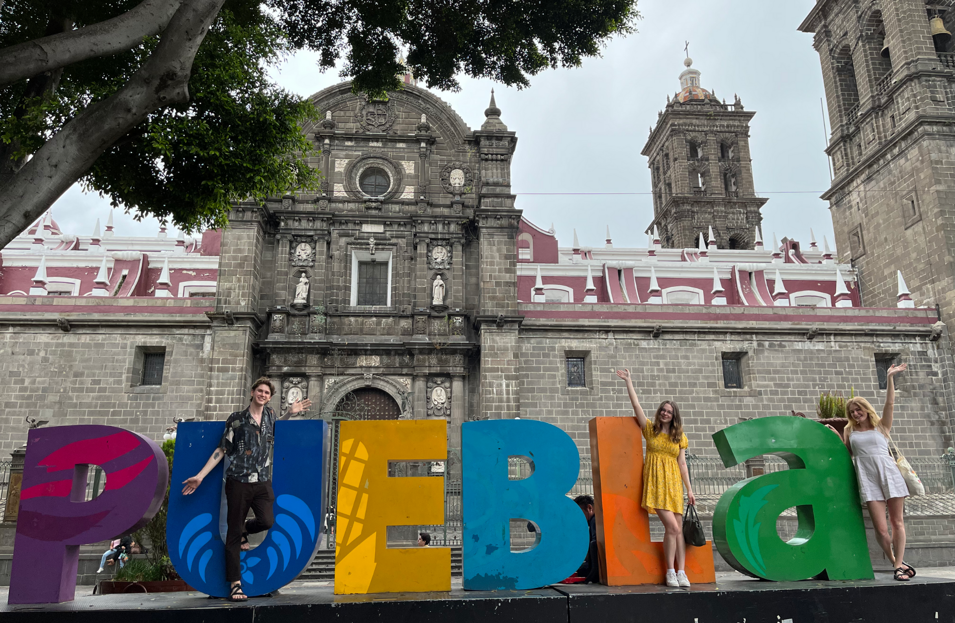 people posing in front of a 3D Street Art of the words 