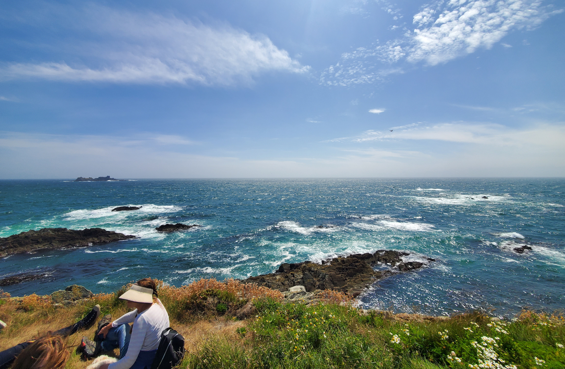 view of the Irish coast with people sitting on the cliffside