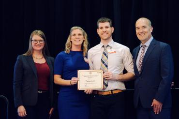 Four people with one holding a certificate that says DecideGuide won third place in the Harriet Stephenson Business Plan Competition