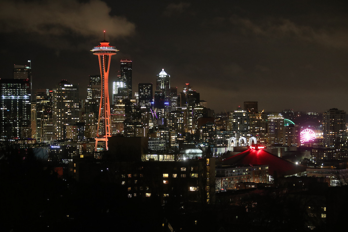 The city of Seattle at night with the Space Needle lit up in red