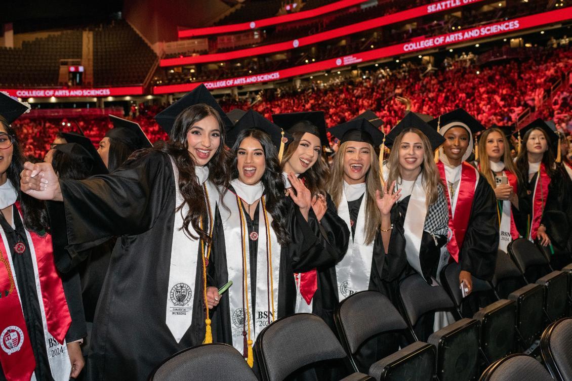 Undergrad students smiling and waving at camera during commencement