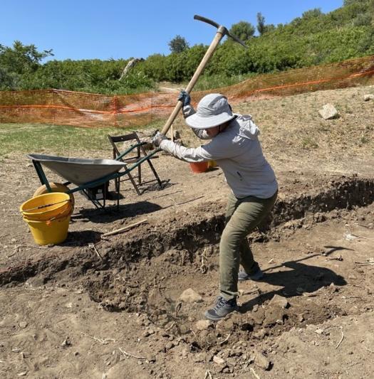 Claire Hood swings a pick ax during an archeological dig