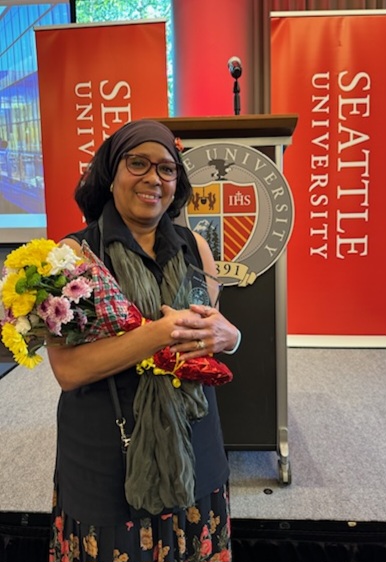 a woman holding flowers in front of a podium and signs