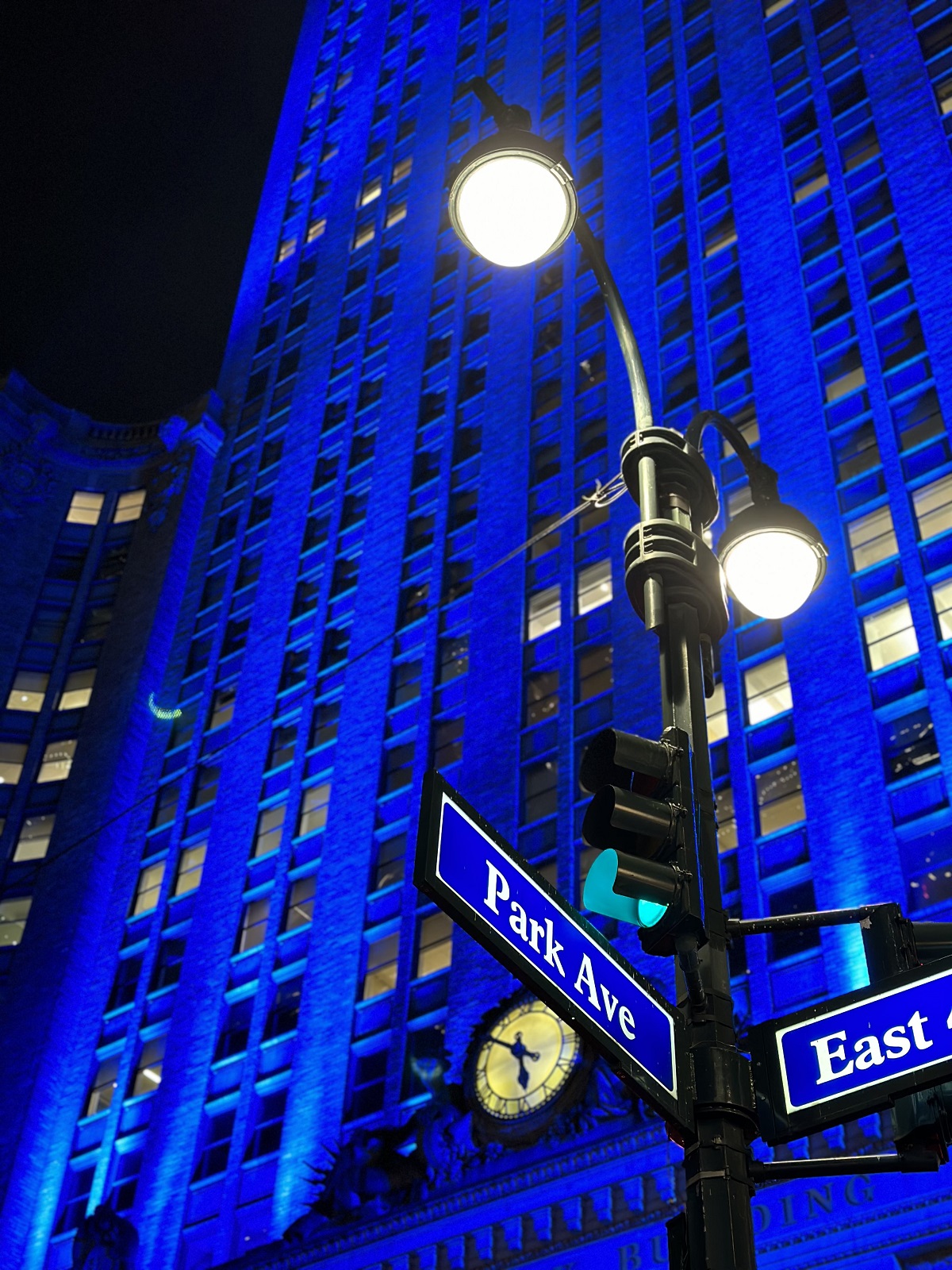 Photo of streetlamp and signs against building lit in blue