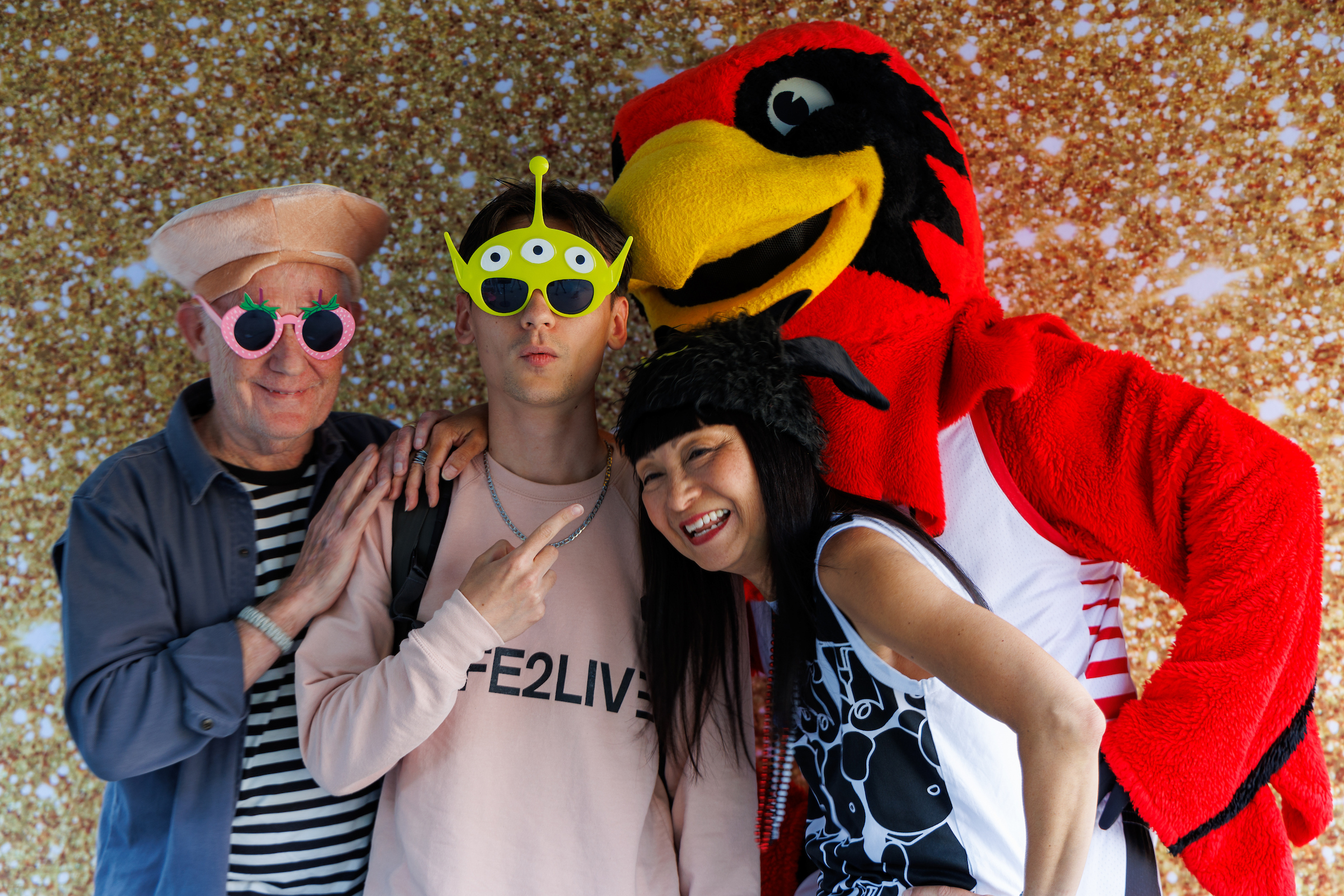a family posing with Rudy and other props against a gold backdrop