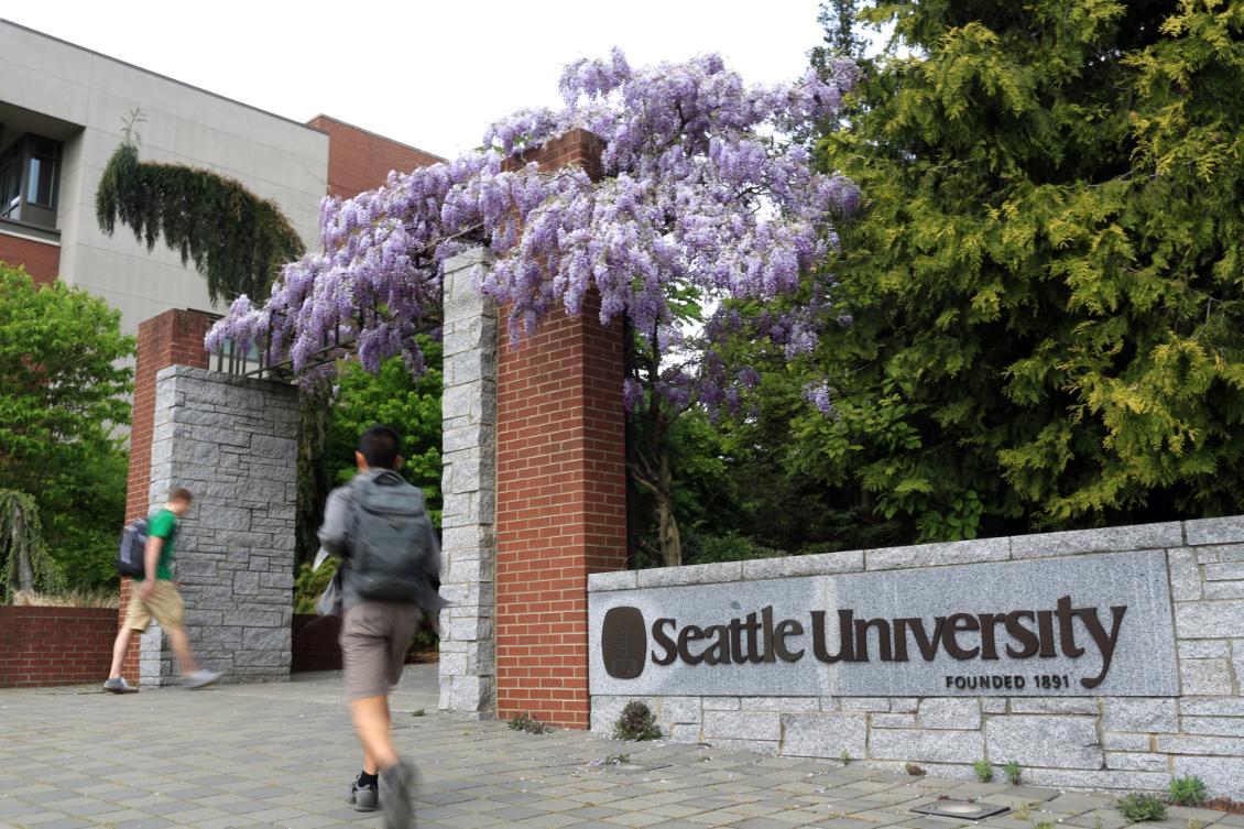 Seattle University sign at south entrance with people walking on sidewalk