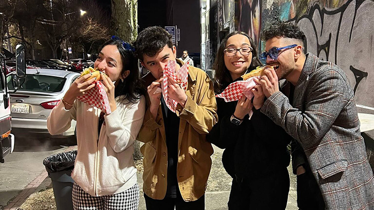 Four people eating Dirty Dog hotdogs