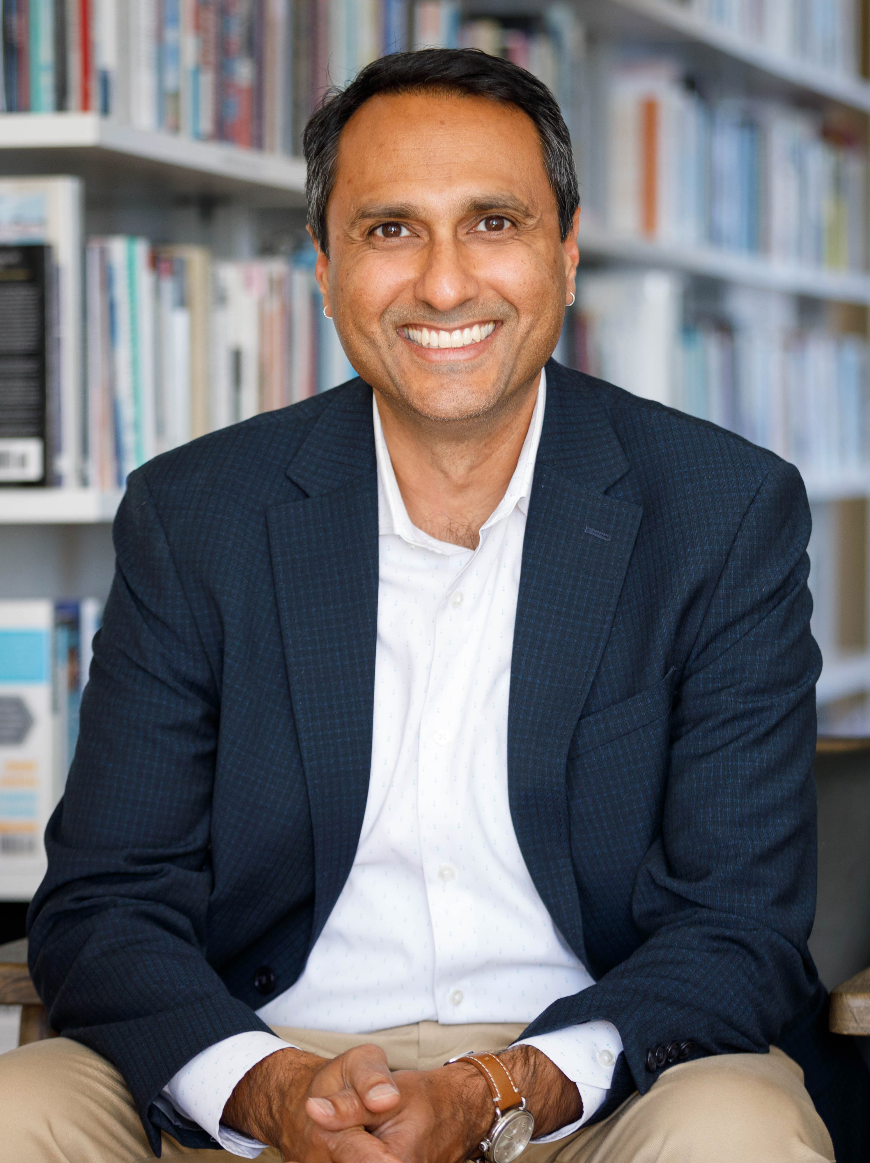 Eboo Patel sitting in a chair in front of a bookshelf